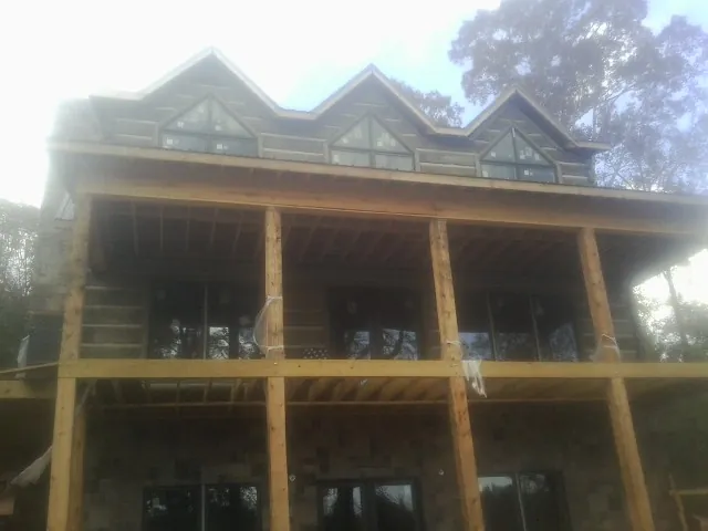 Dormers and porch framing on a large log home under construction — Roof Coating work by our crew in Jadwin