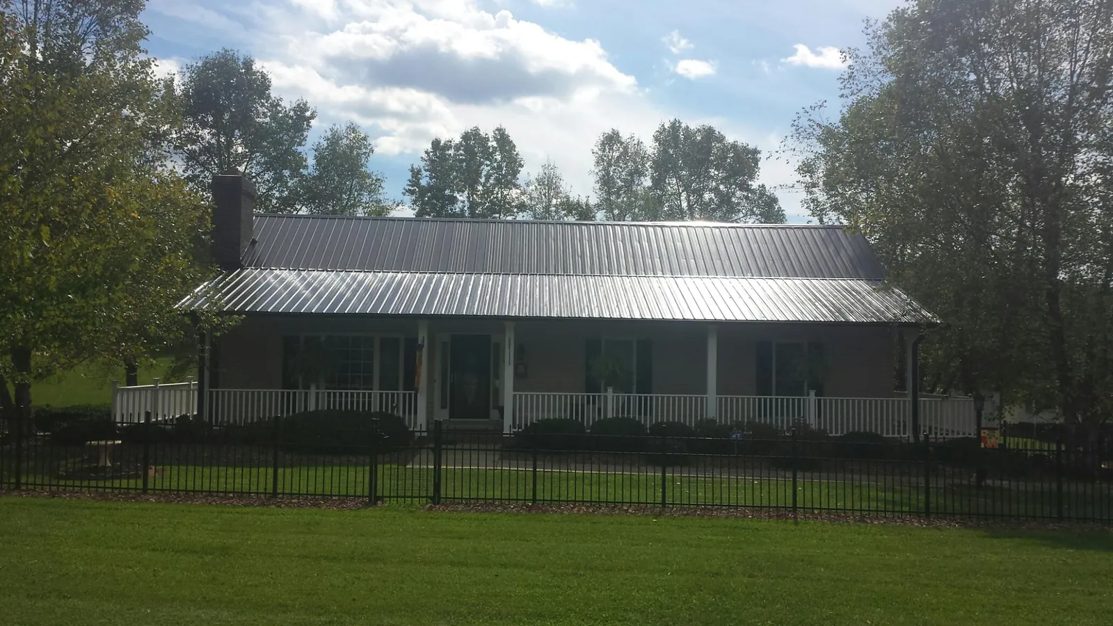 Gray metal roof on a brick ranch with a full width front porch — Gutter Guard Installation work by our crew in Jadwin