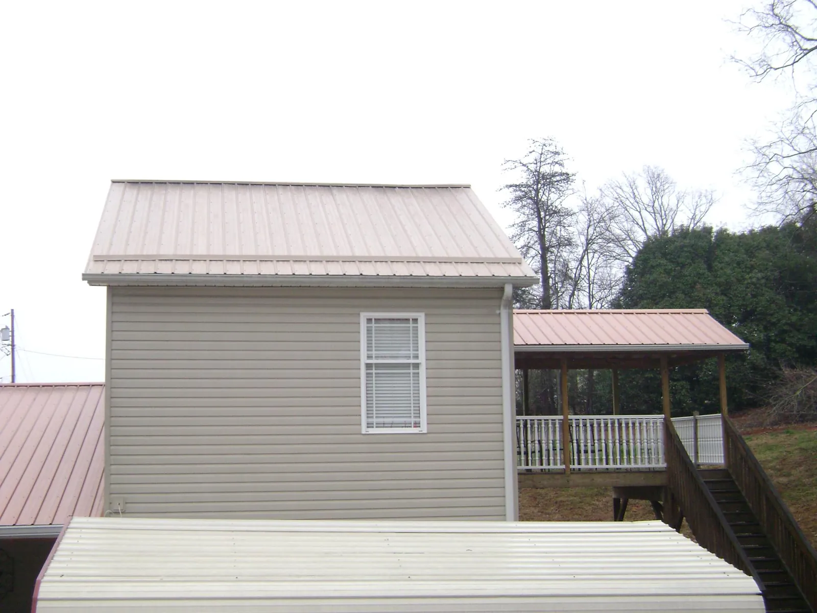 Tan metal roofs on a two story addition and attached porch, from a Roof Replacement job in Jadwin